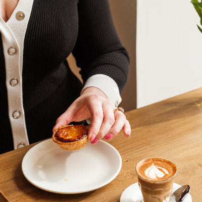 A woman dressed in a smart outfit with a cake and coffee