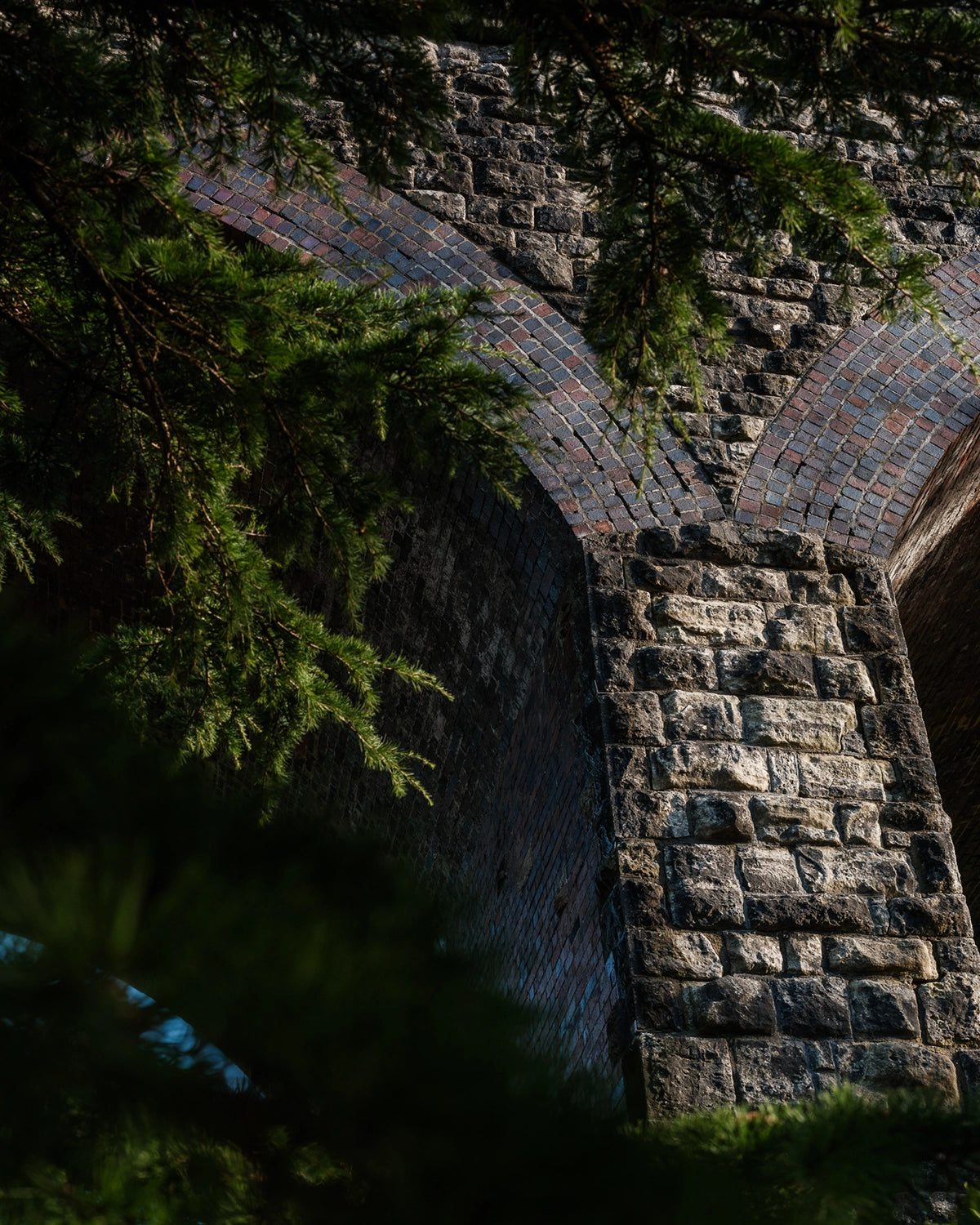 Stone Viaduct archway with greenery on a dark background at Kilver Court & Gardens